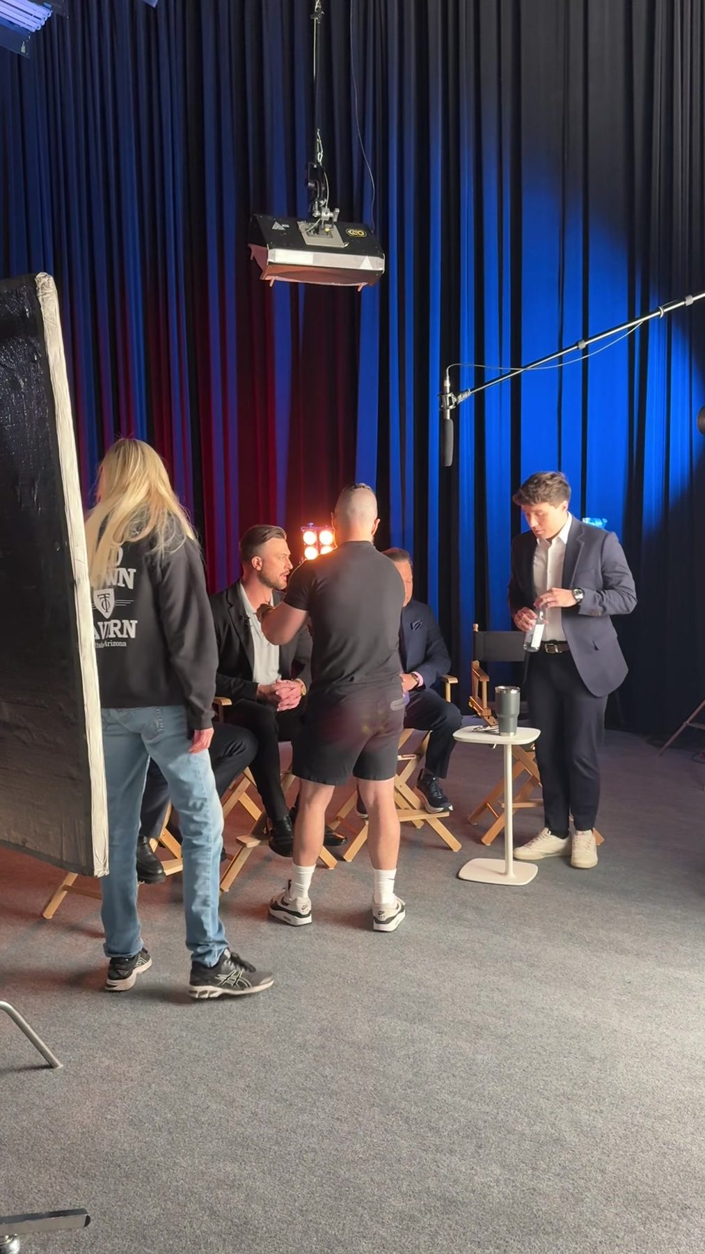 Crew preparing a lit studio set for a panel